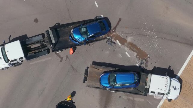 Tow truck hauling smashed vehicle on car accident site. Emergency services responding to traffic crash on American street. First responders helping on road in the USA.