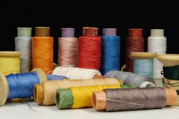 Spools with multi-colored threads on black background, close-up shot