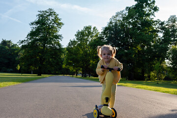 Child with scooter. Yellow riding toddler fun. Summer activity outdoor road.