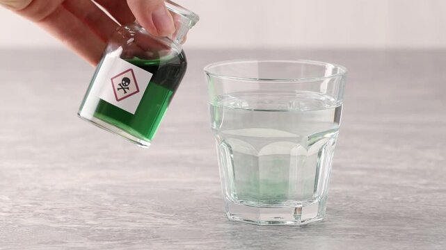 Woman pouring poison from bottle into glass with water at gray table, closeup