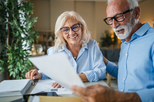 Senior couple discussing financial paperwork at home, planning retirement