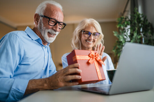 Senior couple celebrating online receiving gift via video call
