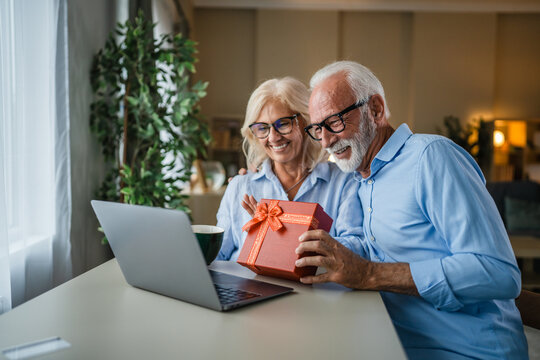 Senior couple celebrating online receiving gift via video call