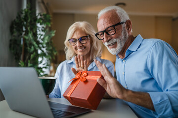 Senior couple celebrating online receiving gift via video call