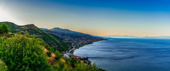 Naklejka premium Panoramic view of Lake Ohrid and the city of Pogradec, Albania with mountains, coastline, and clear evening sky