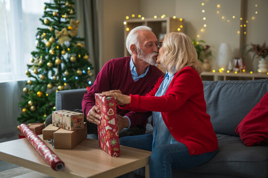 Senior couple kissing while wrapping christmas presents