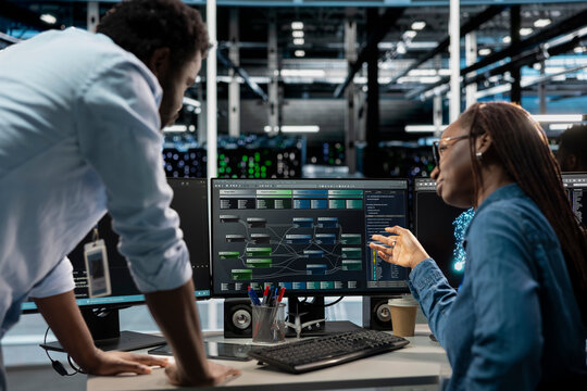 Manager supervising technician programming in server farm housing infrastructure storing datasets. Team leader overseeing IT expert coding, repairing data center racks doing computational operations - Powered by Adobe