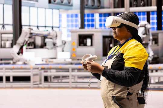 Automation engineer integrates virtual reality into manufacturing process at smart factory. Black female industry 4.0 worker uses VR headset and controllers to enhance training and troubleshooting. - Powered by Adobe