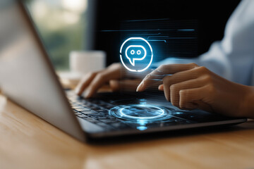Typing on a laptop with a futuristic chat icon, showing interaction and digital communication in a modern work environment.