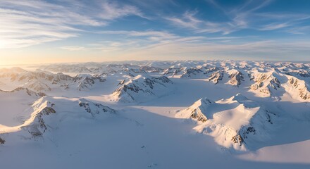 Aerial view of snow covered mountains under a blue and cloudy sky