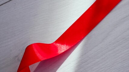 Red satin ribbon on a white wooden floor.
Durable red ribbon for wrapping gifts before the holidays.
Holiday, Christmas, wrapping - Powered by Adobe