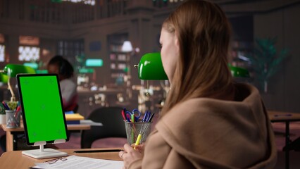 College student looks at isolated chroma key screen at the campus library, working on a school project and collecting information from academic specialty books. Researching. Camera B.
