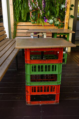 A cozy lounge area in a cafe on an open veranda with chairs and tables. Lush green plants surround...