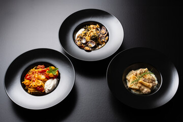 three plates of pasta, spaghetti, linguine and macaroni on a black background