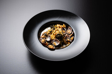 plate of spaghetti with clams on a black background