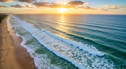 Aerial view of the ocean at sunset with waves and sandy beach