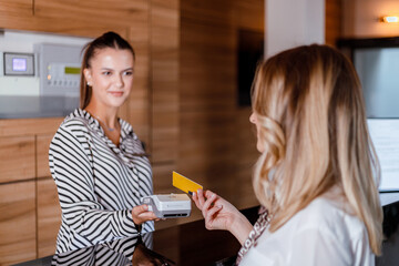 Receptionist hands room key card to guest at hotel front desk during check-in process