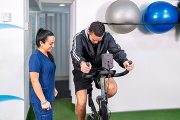 Man exercising on stationary bike with physical therapist