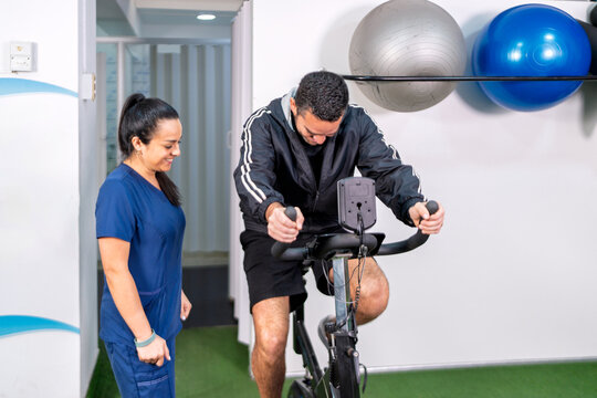 Man exercising on stationary bike with physical therapist