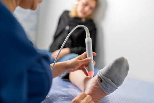 Physiotherapist using laser therapy on patient ankle