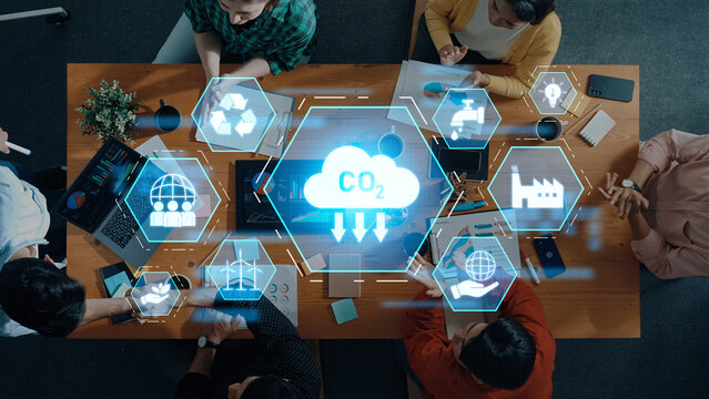 A diverse team collaborates using digital tools to discuss carbon emission reduction strategies, focusing on sustainable development and innovative solutions. Trope - Powered by Adobe