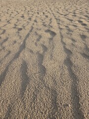Textured Beach Sand with Footprints and Ripples at Golden Hour