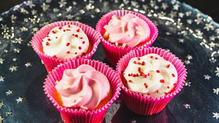 Beautiful pink frosted cupcakes with delicate sprinkles, arranged on an elegant white plate. Perfect sweet treats for birthdays, celebrations or special occasions. Tempting and delightful.
