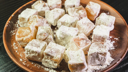A plate of Turkish delight sweets ready to be served. The soft, square candies are dusted with powdered sugar, arranged neatly on a simple plate for an elegant presentation.