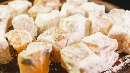 A plate of Turkish delight sweets ready to be served. The soft, square candies are dusted with powdered sugar, arranged neatly on a simple plate for an elegant presentation.