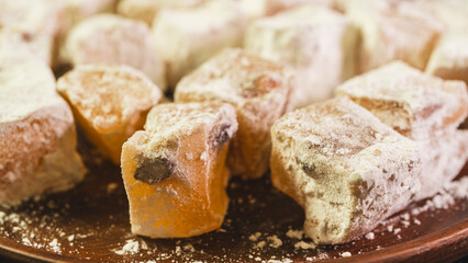 A plate of Turkish delight sweets ready to be served. The soft, square candies are dusted with powdered sugar, arranged neatly on a simple plate for an elegant presentation.