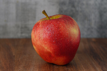 Red apple with water drops on wooden table