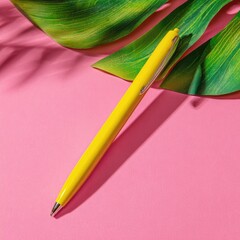 Bright Yellow Pen On Pink Background With Tropical Leaf