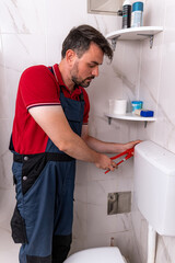 Man repairing bathroom toilet in modern home setting during daytime