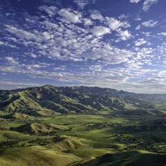Naklejka premium Scenic View Of Green Valley With Mountains Under Sunny Sky