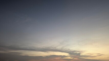 A soft, tranquil dawn sky transitioning from deep blue gray to pale yellow pink at the horizon. Peaceful abstract background texture of clouds light.