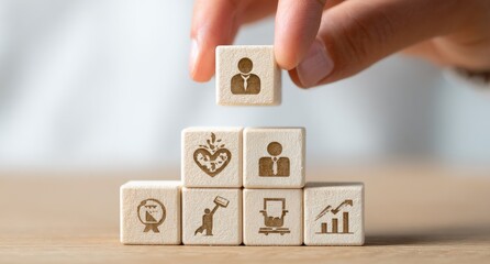 Hand placing a wooden block with a person icon atop a stack of blocks with various business icons