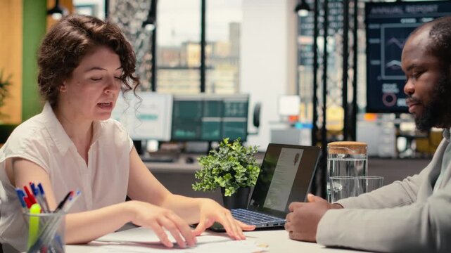 HR professional handing over the paper with job benefits package for candidate to review, checking contract details. Company offering retirement plans and wellness programs. Camera B.