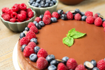 Delicious chocolate cheesecake with berries and mint on wooden table, closeup