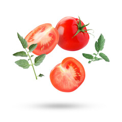 Fresh ripe tomatoes and green leaves falling against white background