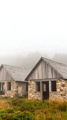 Obraz premium Two rustic cabins in a misty mountain landscape