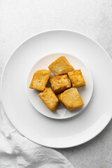Overhead view of fried tofu in chopsticks, top view of pan fried soya bean tofu cubes