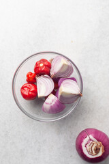 Overhead view of purple onions and scotch bonnet pepper on a white countertop, top view of onions...