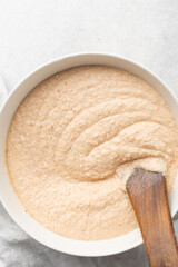 Overhead of moi moi mixture in a white ceramic bowl, top view of nigerian bean pudding being mixed, process of making nigerian moi moi