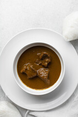 Overhead view of miyan kuka and tuwon on a white plate, top view of northern nigerian miyan kuka soup and rice swallow or tuwon shinkafa