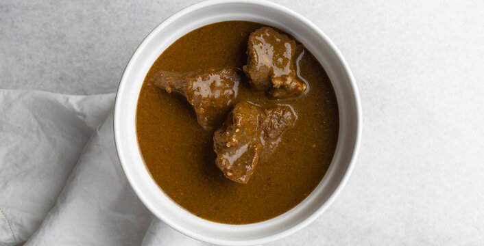 Overhead view of miyan kuka and tuwon on a white plate, top view of northern nigerian miyan kuka soup and rice swallow or tuwon shinkafa