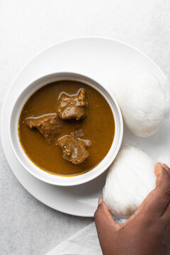Overhead view of miyan kuka and wrapped tuwo shinkafa in a white bowl, top view of northern nigerian food and soup