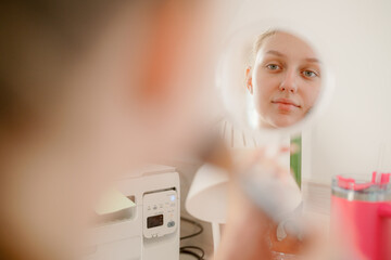 A young woman focuses on applying makeup in front of a mirror. Her expression is calm as she perfects her look, surrounded by beauty tools and a soft atmosphere.