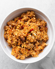 Overhead view of tomato scrambled eggs in a white bowl, top view of egg fried in tomato sauce