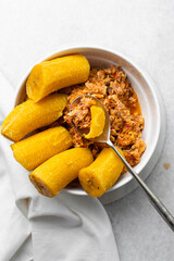 overhead view of Boiled ripe plantain with tomato scrambled eggs in a white bowl, top view of nigerian egg and plantain