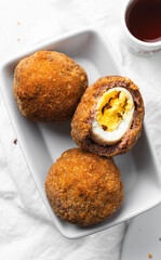 Overhead view of fried scotch eggs on white countertop, top view of cross-section of scotch eggs